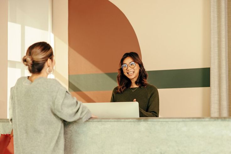 Friendly receptionist assisting a young woman at the front desk